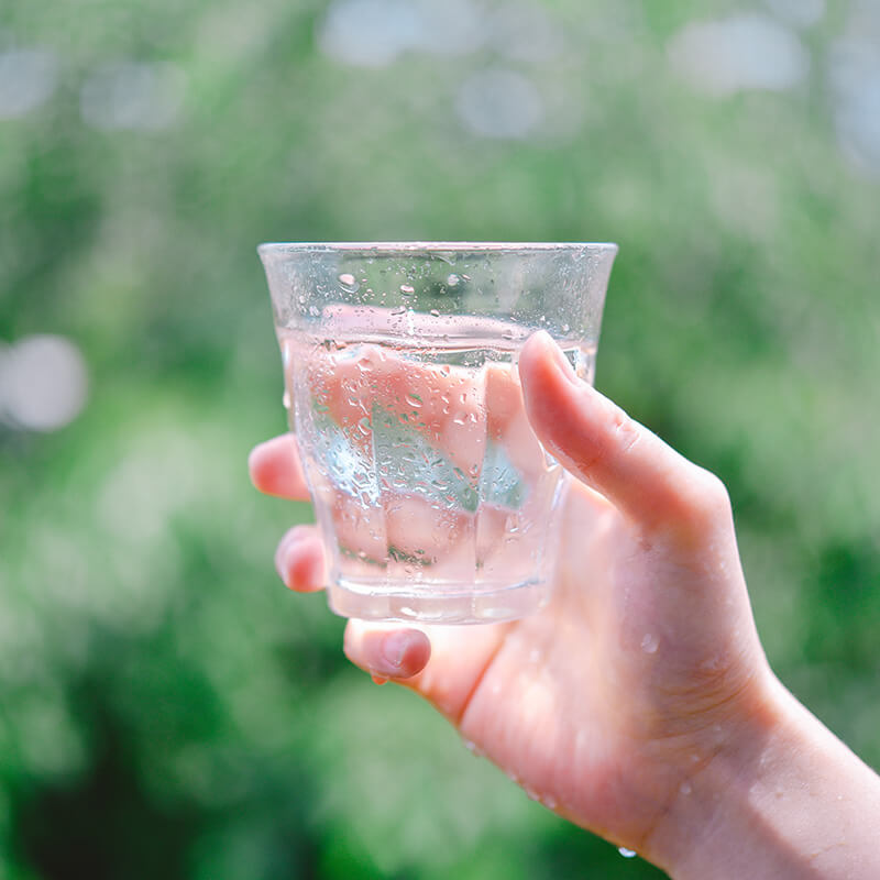 Someone holding up a glass of water.