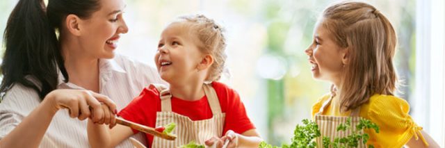 Woman happily cooking with two daughters