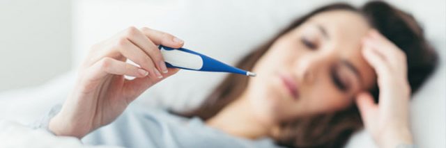 Woman with fever holding thermometer