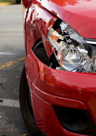 A red car with a damaged headlight after an accident