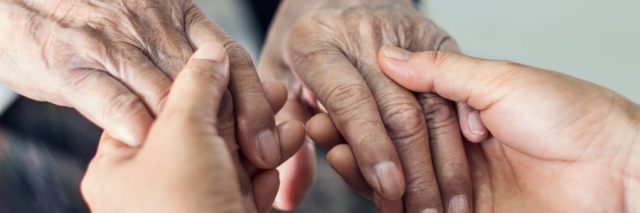 Adult holds the hands of an elderly person