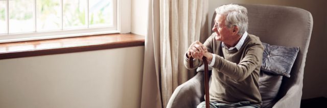 Elderly man in wheelchair stares outside window