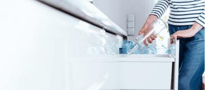 Women throwing glass bottle in recycle bin