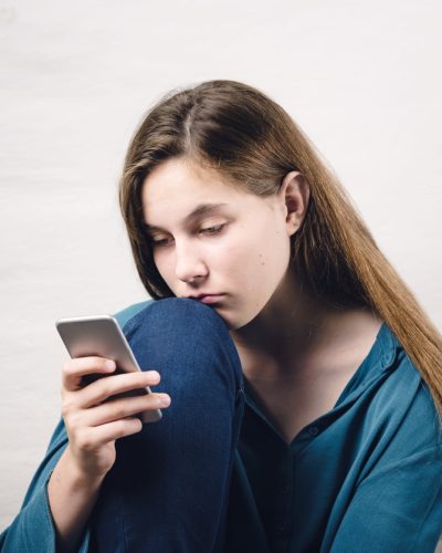 Young girl looking sad at phone