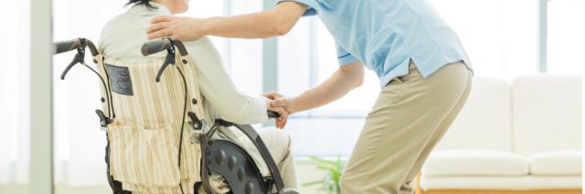 Nursing home worker tends to elderly patient in wheelchair