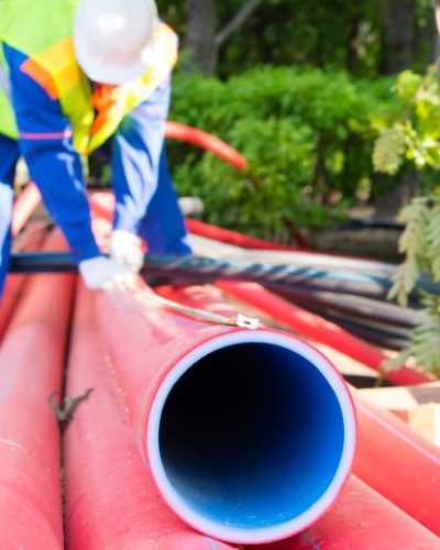 Construction worker handling red pipes
