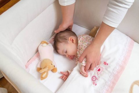 Baby sleeping in crib with bumpers