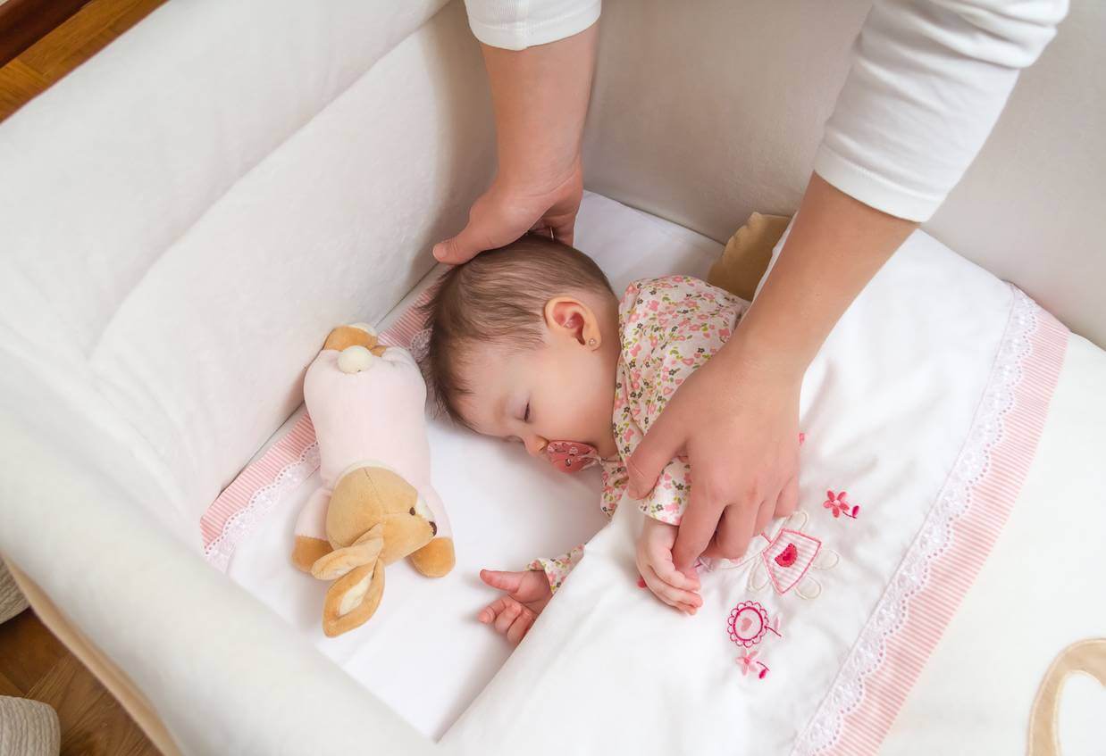 Baby sleeping in crib with bumpers