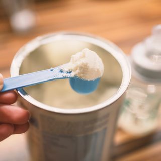 Scoop of baby formula with can and bottle