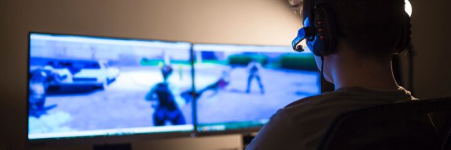 boy playing an online game on monitors