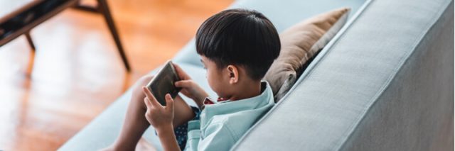 boy sitting on couch using smartphone