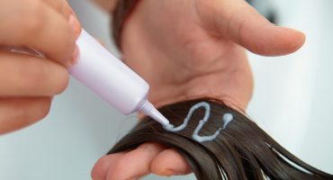 Woman applying chemical hair straightener to her hair