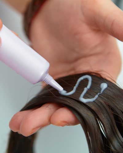 Woman applying chemical hair straightener to her hair
