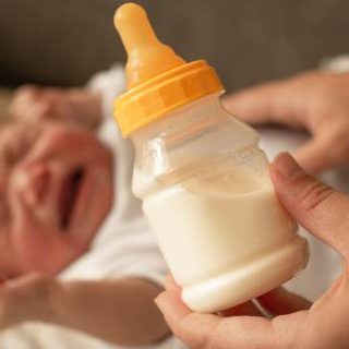 Crying baby with bottle of formula