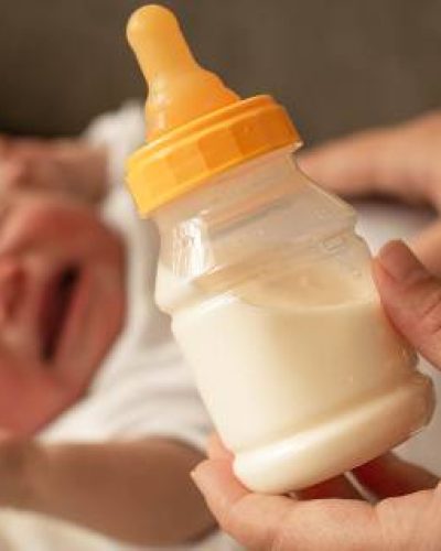 Crying baby with bottle of formula