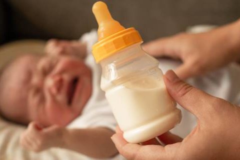 Crying baby with bottle of formula