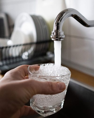 Someone filling a glass with tap water.