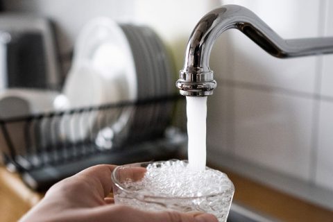 Someone filling a glass with tap water.
