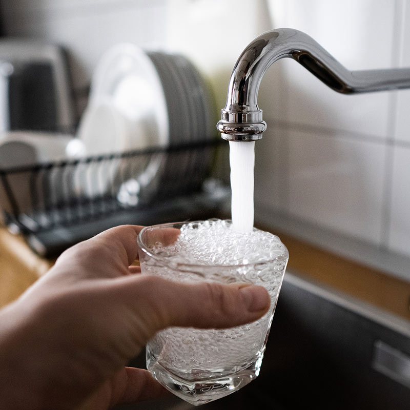 Someone filling a glass with tap water.