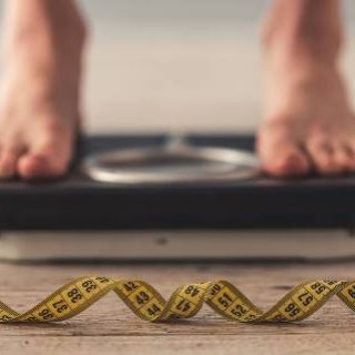 Bare feet on scale with tape measure