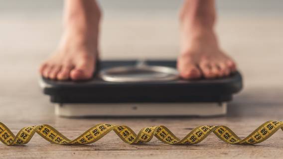 Bare feet on scale with tape measure