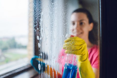 Young woman washing window