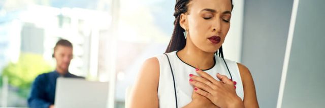 Woman experiencing heartburn at her desk