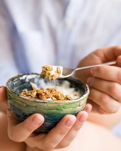 Person eating granola in yogurt