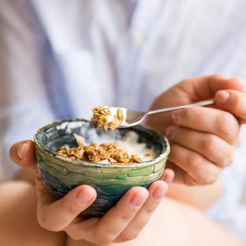 Person eating granola in yogurt