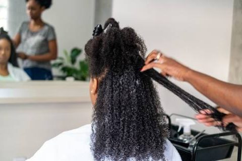 Woman having hair straightened in salon