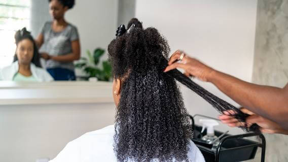 Woman having hair straightened in salon