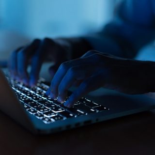 Hands in dark on computer keyboard