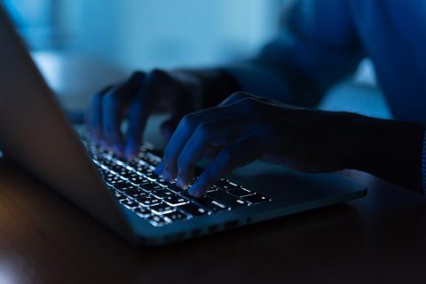 Hands in dark on computer keyboard