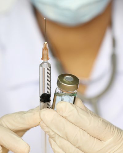 Doctor hand holding draw syringe and medicine bottle on white background
