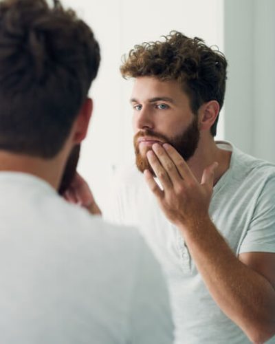 Man checks his face in the mirror