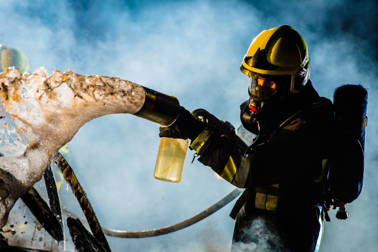 Firefighter spraying foam from hose