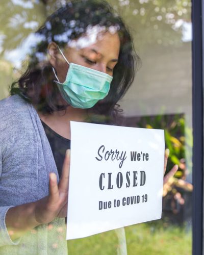 Female store owner closes shop and puts up sign