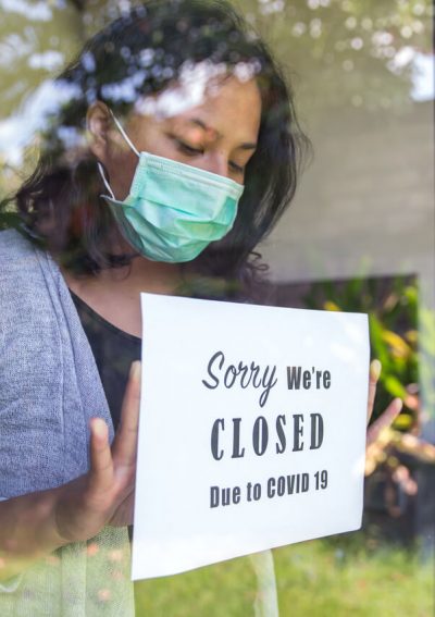 Female store owner closes shop and puts up sign