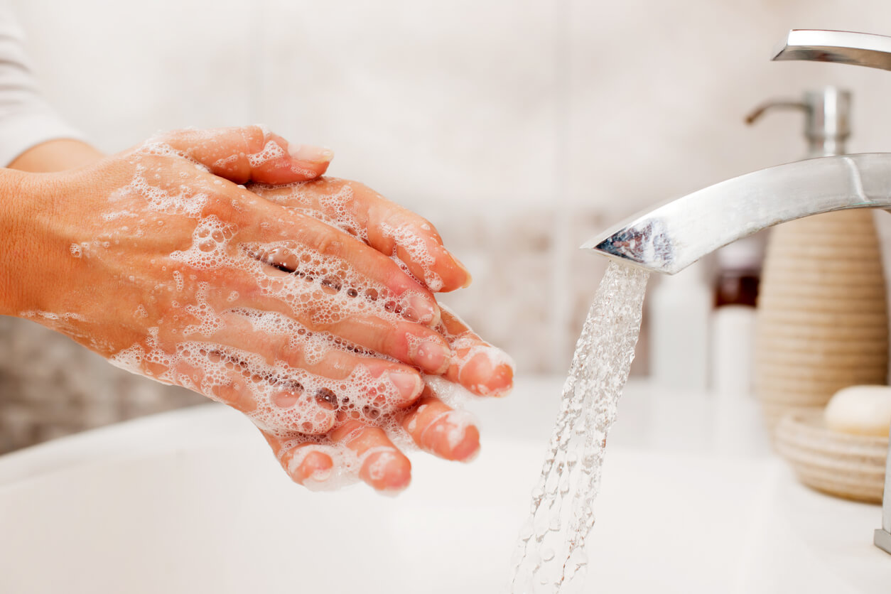 Hands with soap being washed in a sink.
