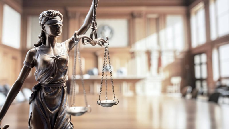The scales of justice with a courtroom in the background