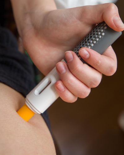 A woman uses an injection pen on her thigh.