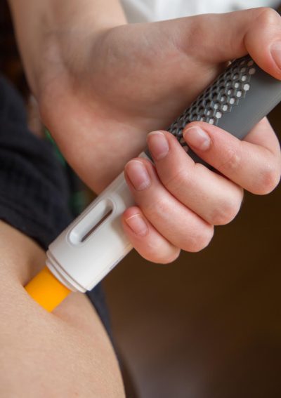 A woman uses an injection pen on her thigh.