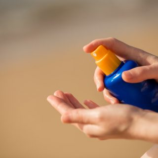 Person spraying sunscreen into their hand