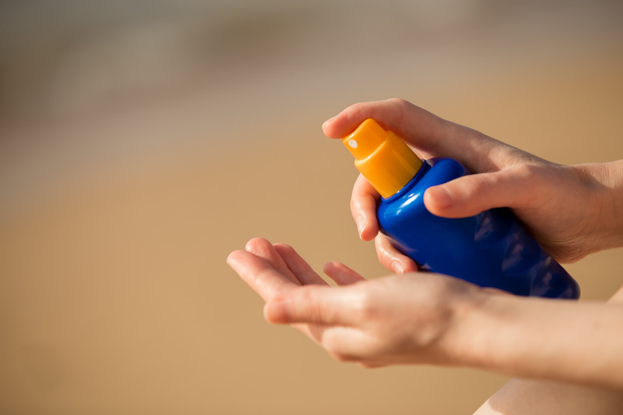 Person spraying sunscreen into their hand