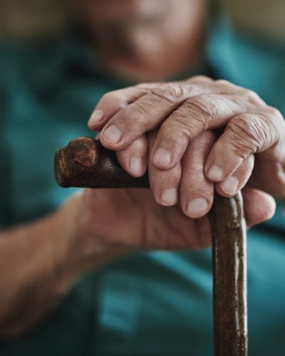 Elderly man holding onto a cane