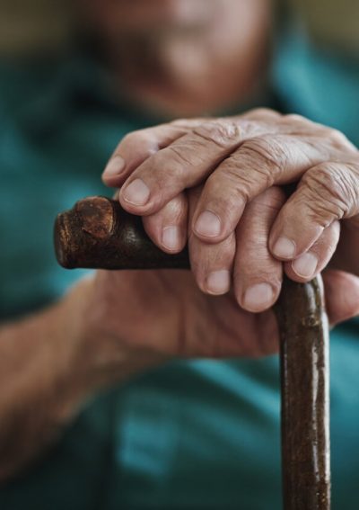 Elderly man holding onto a cane