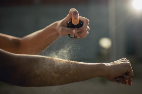 Person spraying aerosol sunscreen on their arm