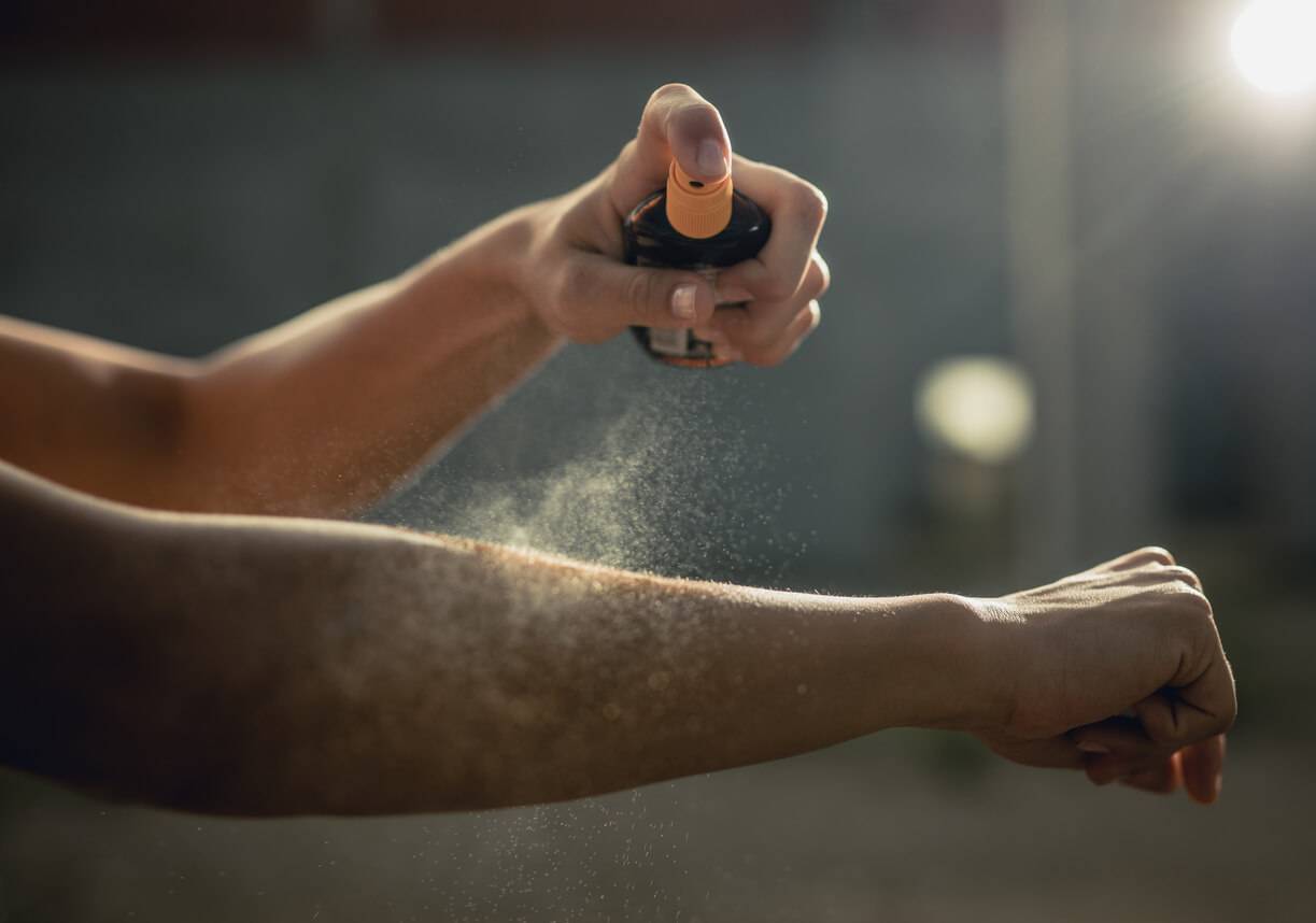 Person spraying aerosol sunscreen on their arm