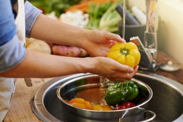 Woman washes vegetables in the sink