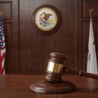 Gavel and flags with Illinois seal in courtroom